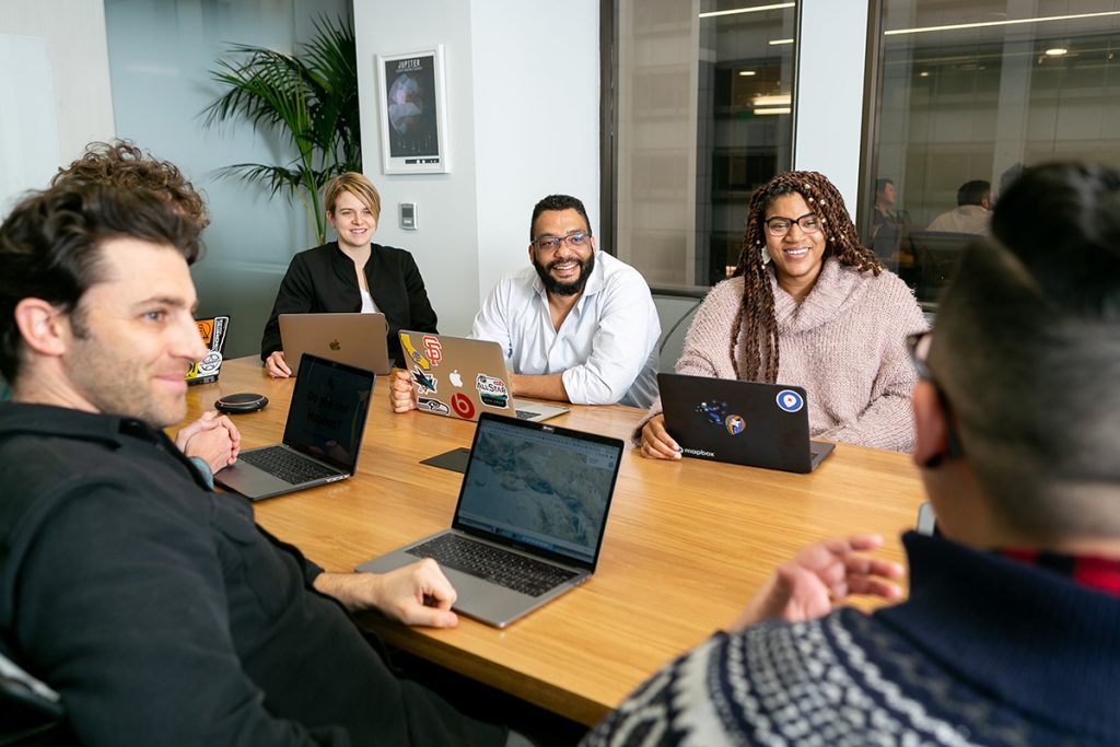 A confident team member discusses ideas at a team meeting or conference table.